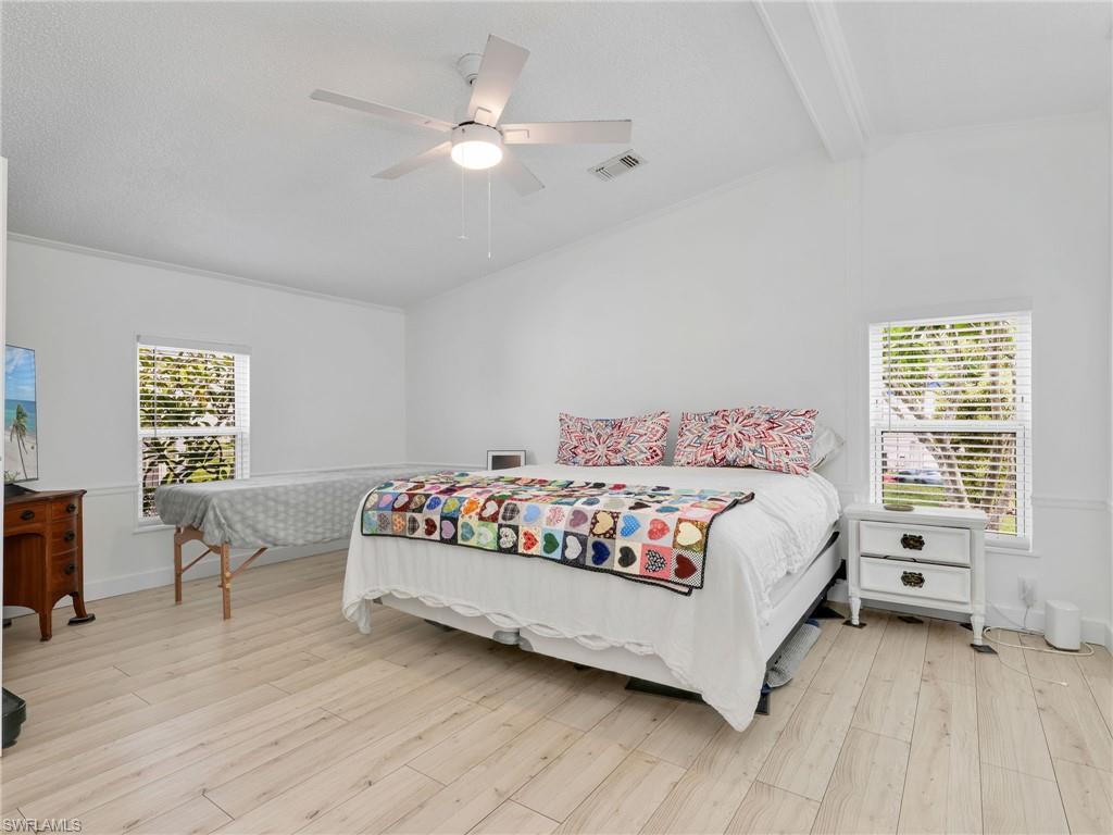 Bright interior featuring light wood-finish flooring, white walls, and a vaulted ceiling with exposed beams