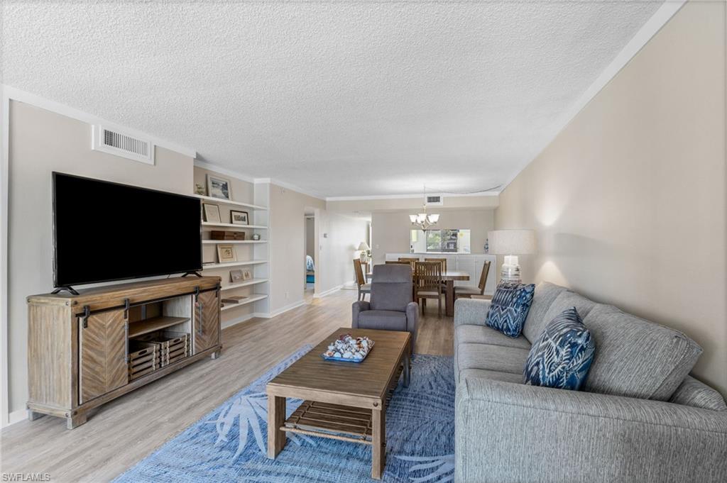 Living room featuring a textured ceiling, a chandelier, wood finished floors, and built in features