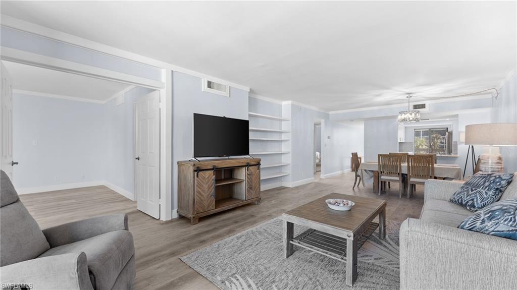 Living area featuring ornamental molding, light wood finished floors, and a chandelier