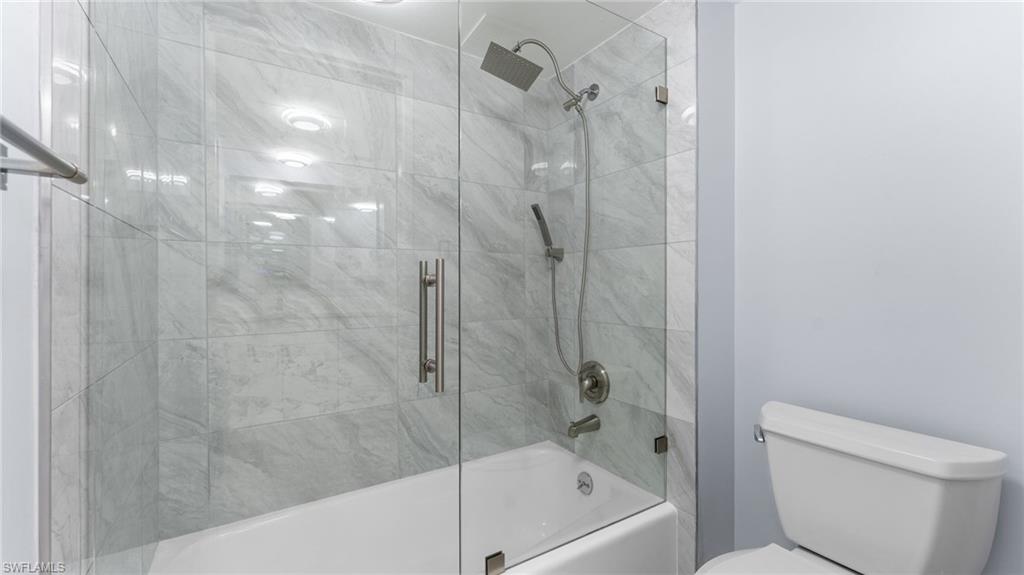 Full bathroom with combined bath / shower with glass door and toilet