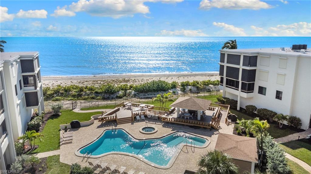 Water view with a fenced backyard, local beach, and an outdoor fire pit
