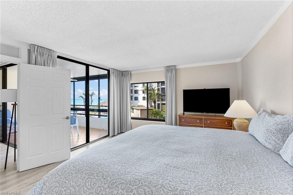 Bedroom featuring a textured ceiling, floor to ceiling windows, access to exterior, and light wood-style flooring