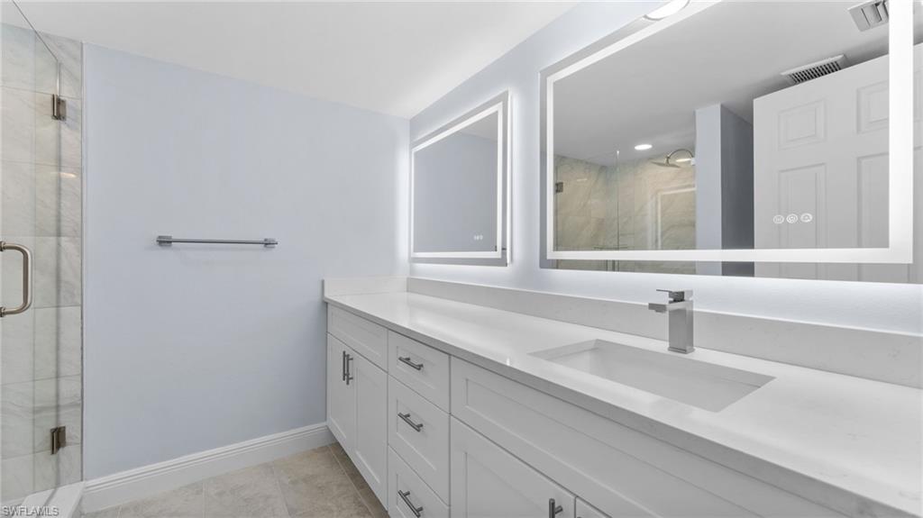 Full bath featuring vanity, a stall shower, and light tile patterned flooring