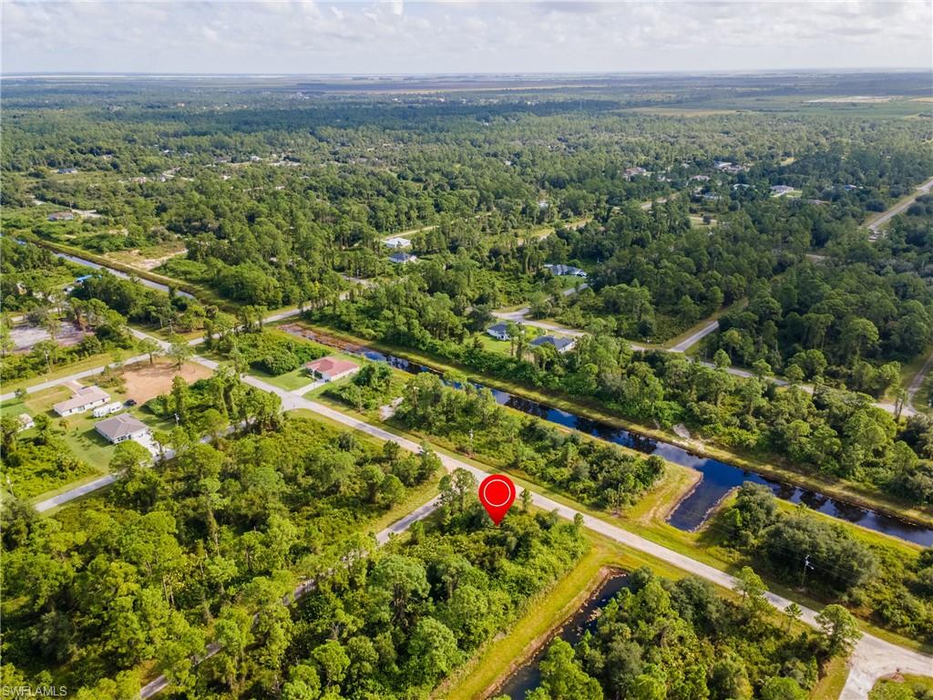 Aerial view of property and surrounding area with a heavily wooded area and a nearby body of water