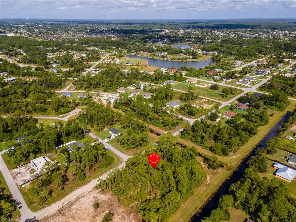 Aerial view of property and surrounding area featuring a large body of water and a tree filled landscape