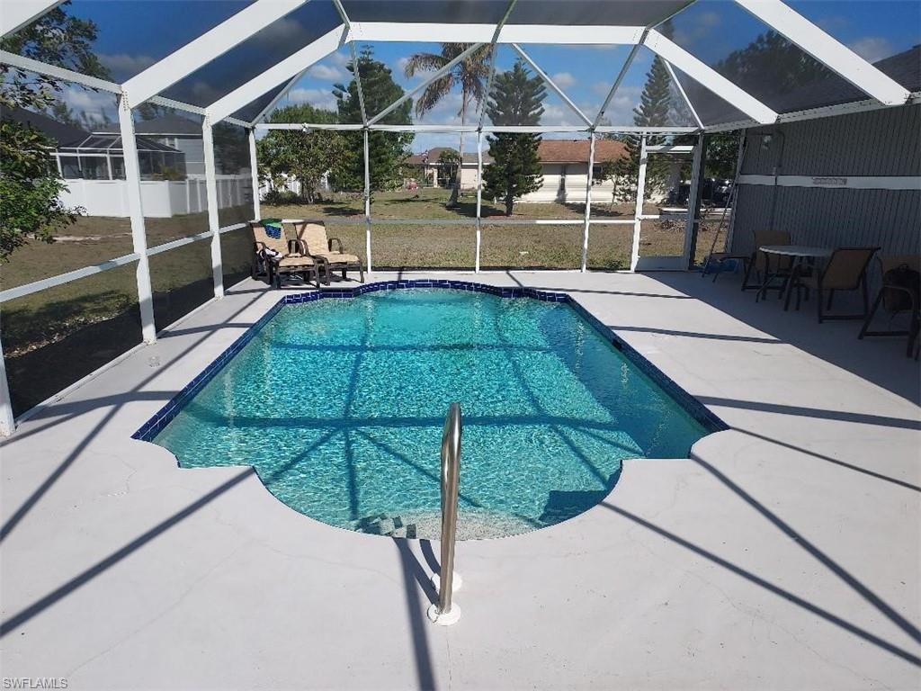 Screened swimming pool with a curved entry, surrounded by a concrete deck and a white aluminum enclosure