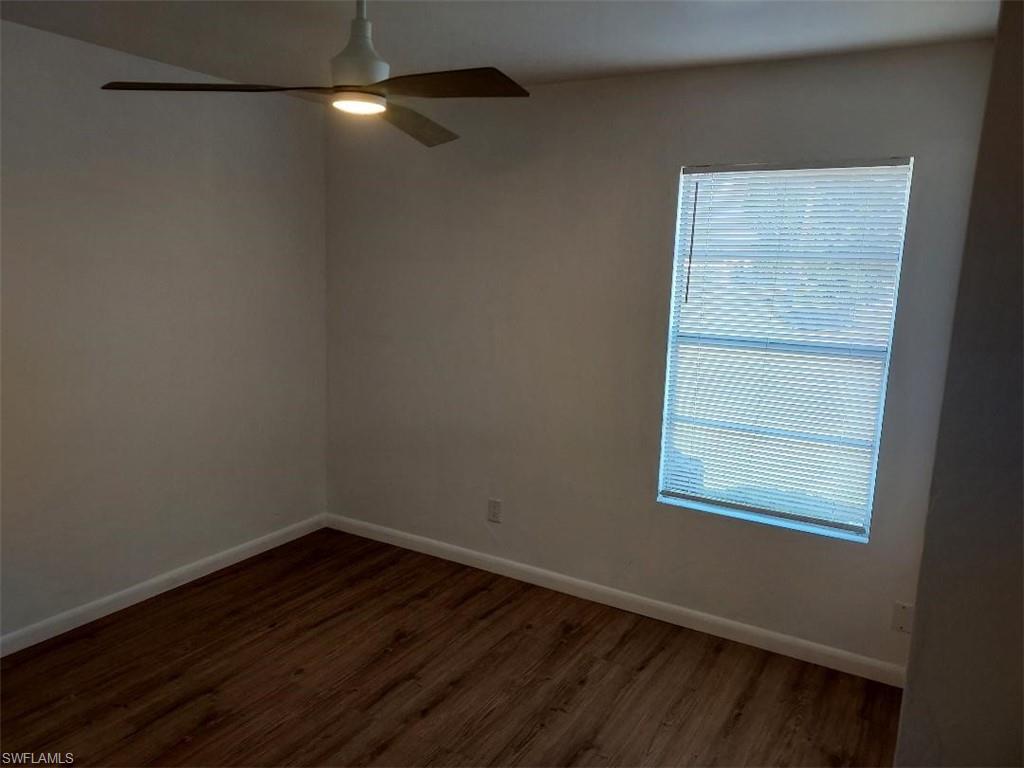 Room featuring wood-finish flooring, white baseboards, a single window with blinds, and a ceiling fan with integrated lighting