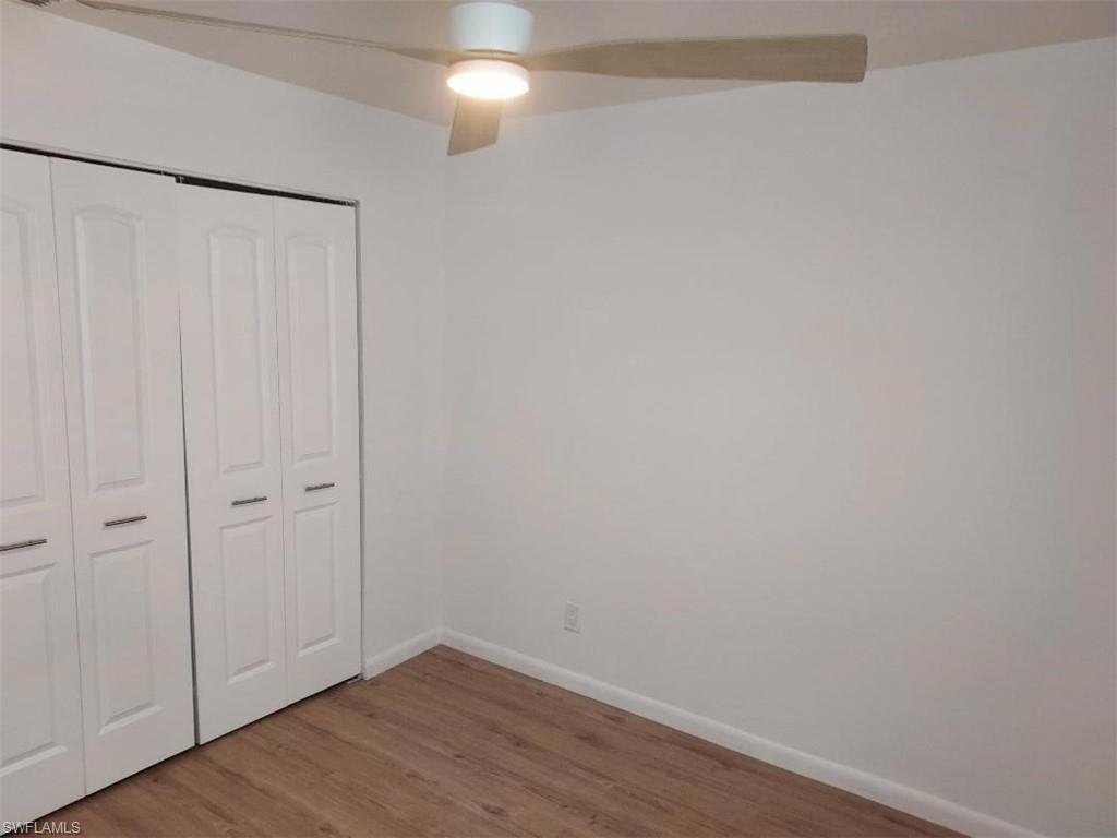 Interior room featuring wood-finish flooring, white walls, and a contemporary ceiling fan with integrated lighting