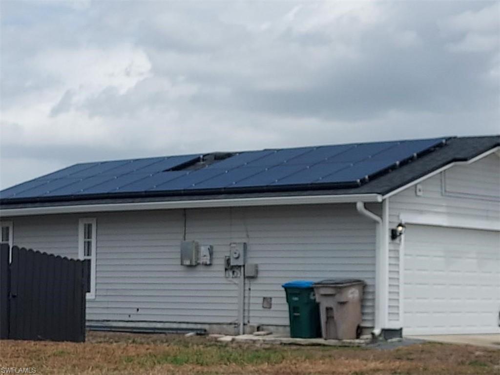 Roofline featuring solar panel array, dark shingle roofing, and white gutter system