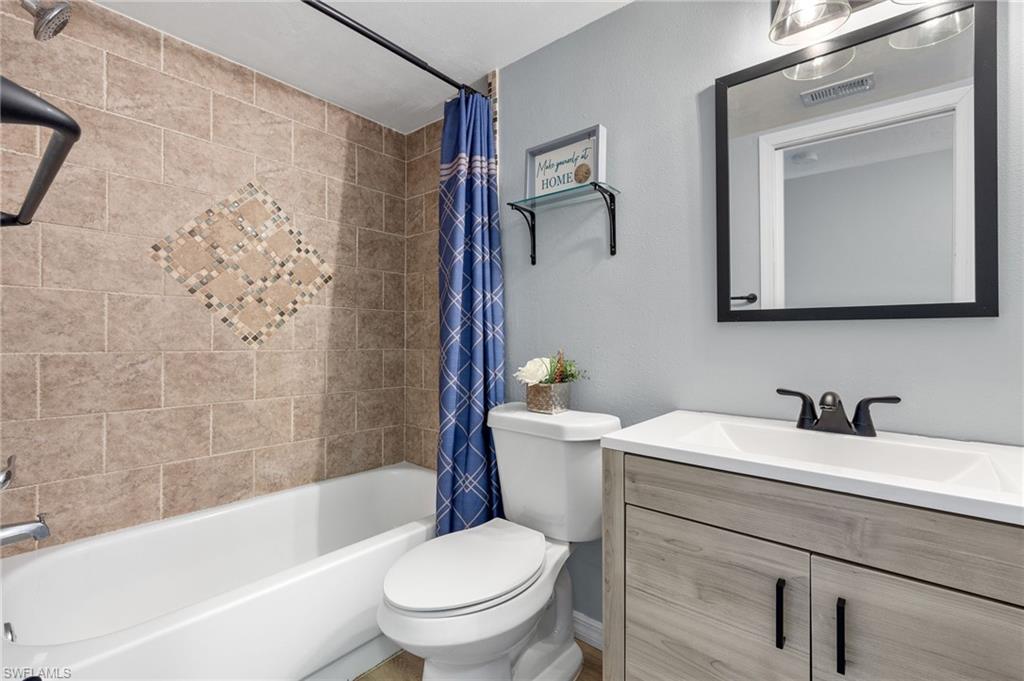 Full bathroom featuring shower / bathtub combination with curtain, vanity, and toilet