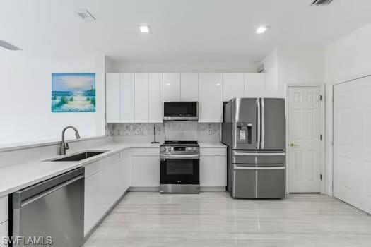 Kitchen featuring stainless steel appliances, white cabinetry, modern cabinets, and light countertops