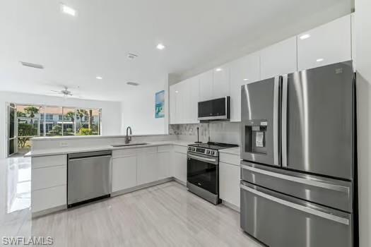 Kitchen featuring appliances with stainless steel finishes, modern cabinets, white cabinetry, light countertops, and recessed lighting