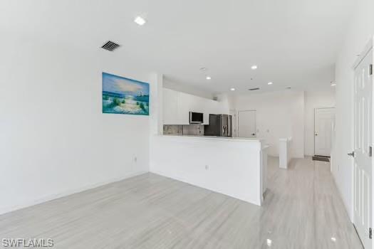 Dining room with light wood finished floors and recessed lighting