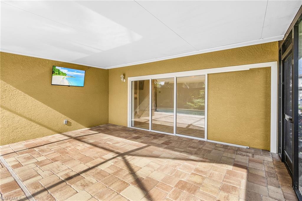 Screened patio with paver flooring, textured stucco walls, and multi-panel sliding glass doors