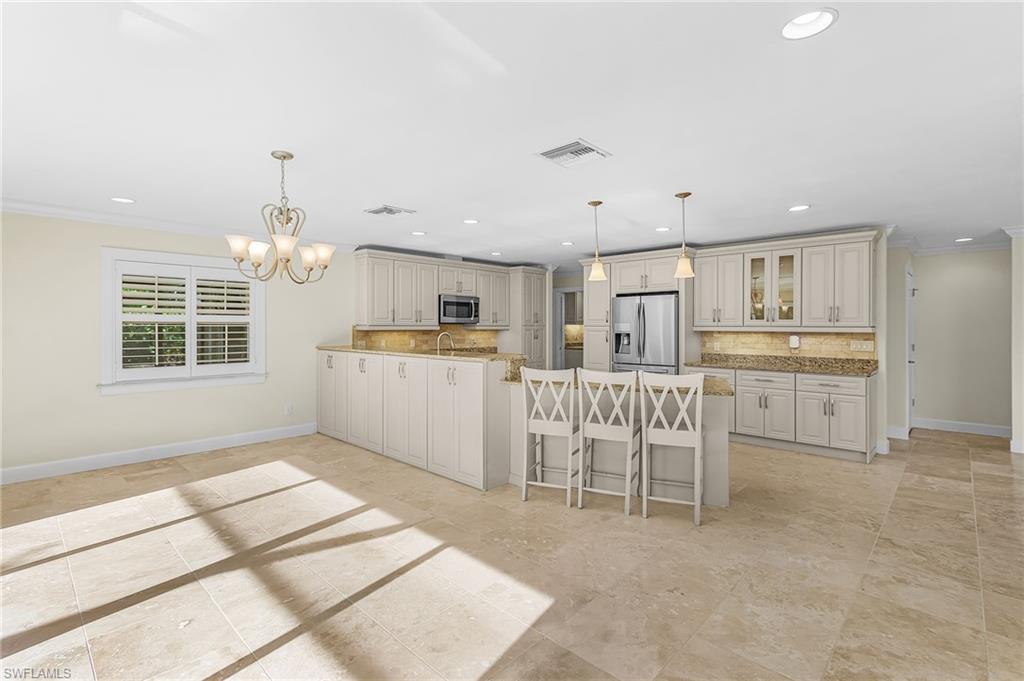 Open-concept kitchen and dining area featuring light-toned cabinetry, granite countertops, and stainless steel appliances