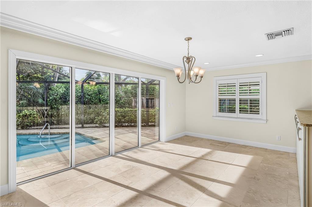 Spacious room featuring large sliding glass doors opening to a screened pool area, neutral-toned tile flooring, a decorative chandelier, recessed lighting, and a window with white plantation shutters