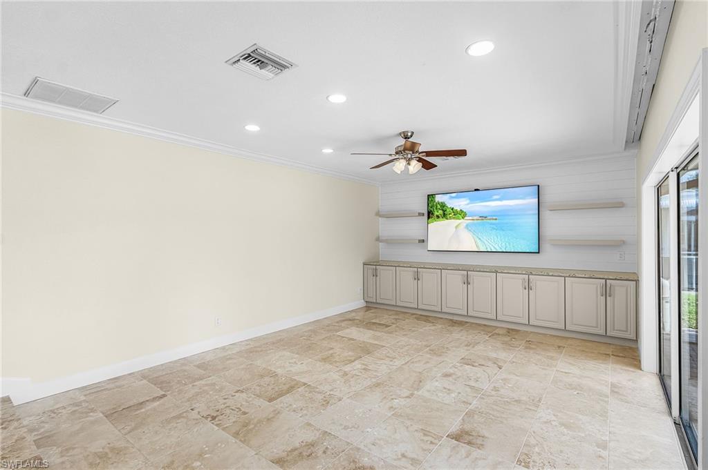 Spacious room featuring large format tile flooring, a built-in media console with extensive cabinetry and countertop space, shiplap wall accent, recessed lighting, and a ceiling fan