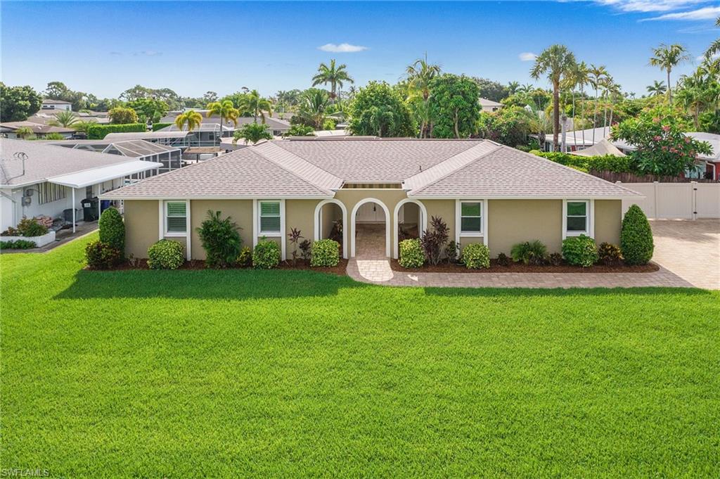 Single-story residence featuring a neutral-toned exterior, a gabled roofline, and a mature green lawn