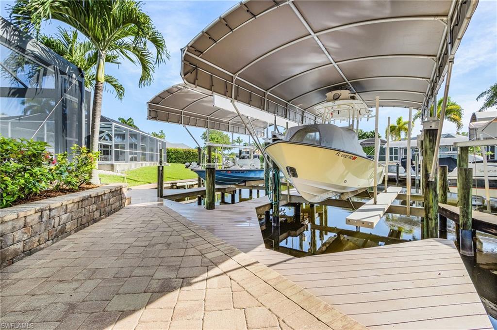 Dock area featuring a boat lift with a canopy, composite decking, and a paver pathway