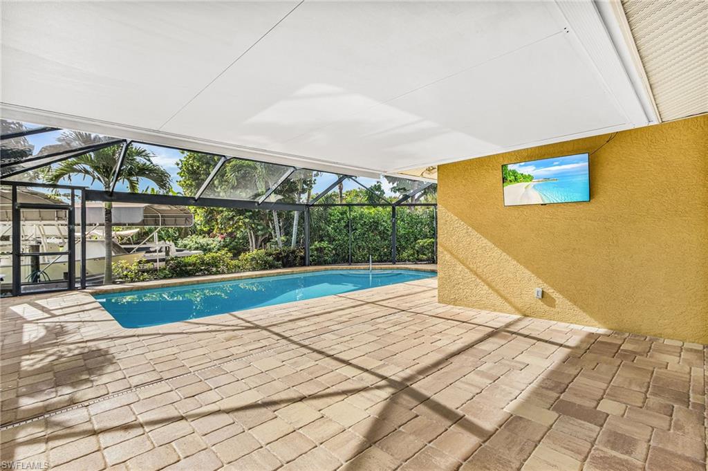 Screened patio featuring a swimming pool, paver flooring, and a textured wall