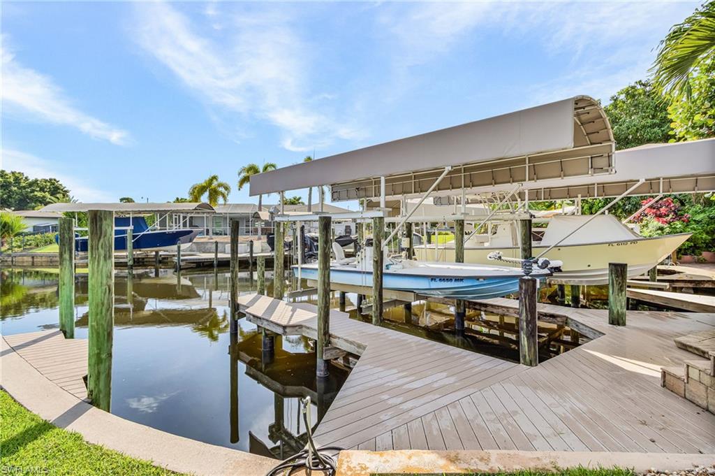 Waterfront property featuring multiple boat slips with covered lifts, composite decking, and direct canal access