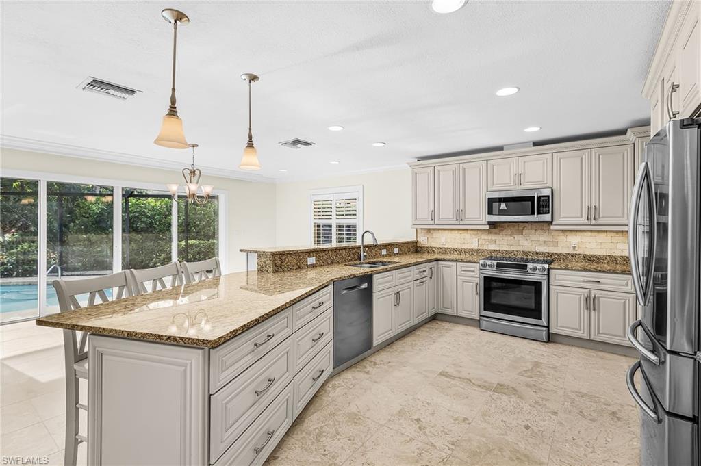 Spacious kitchen featuring light-toned cabinetry, stainless steel appliances, granite countertops, and tile flooring
