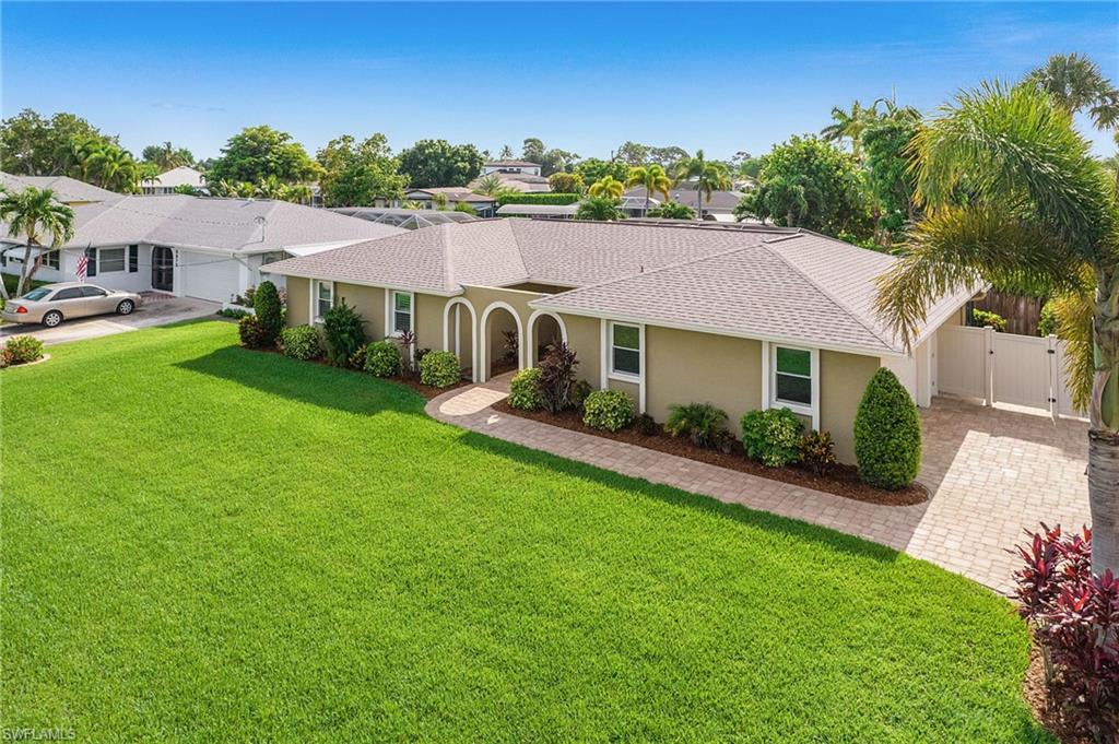 Expansive green lawn fronts a stucco exterior home featuring a curved entry archway and a paver walkway