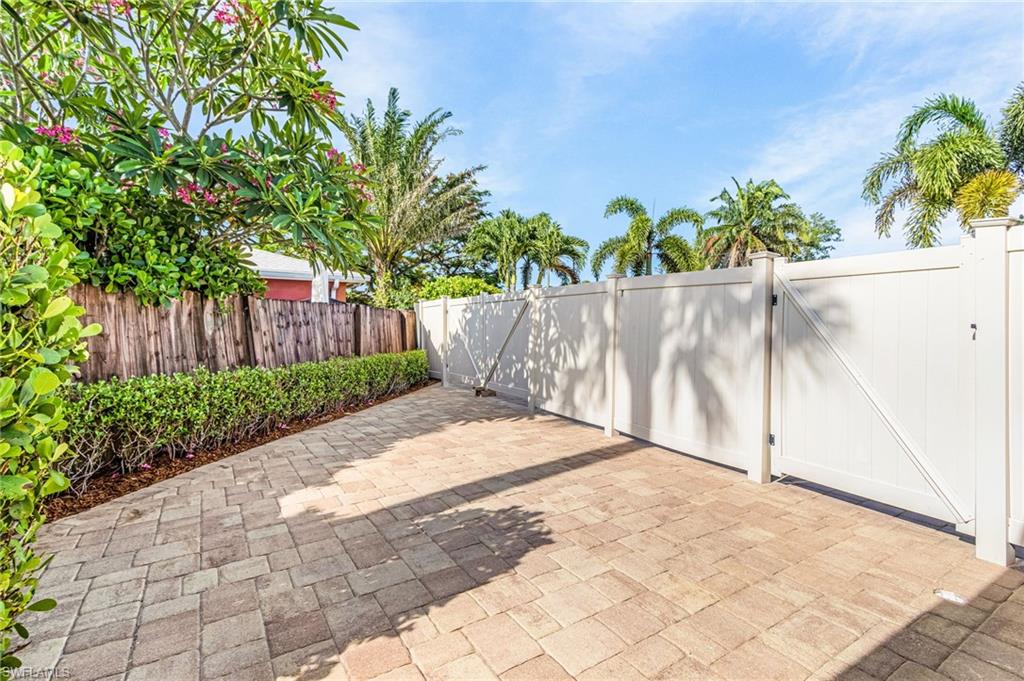 Paver pathway bordered by manicured hedges and a wooden fence