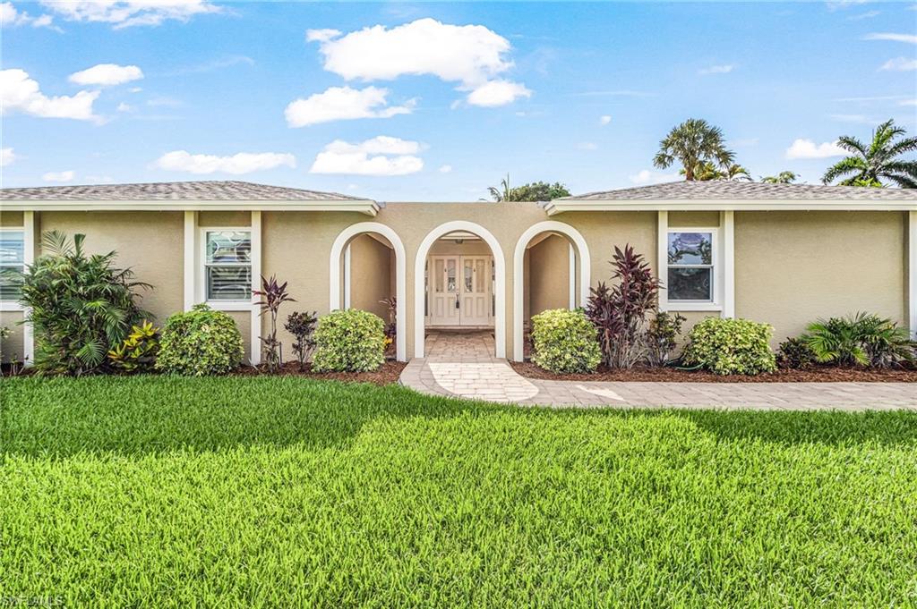 Stucco exterior featuring an arched entryway with decorative double doors