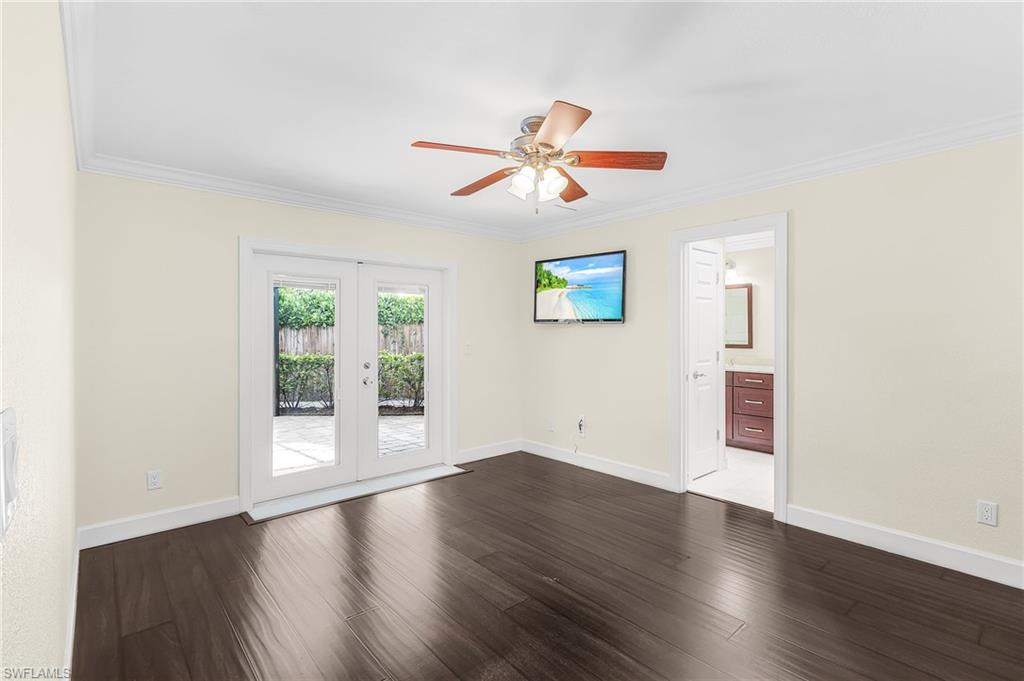 Expansive room featuring dark wood-finish flooring, white baseboards, and crown molding