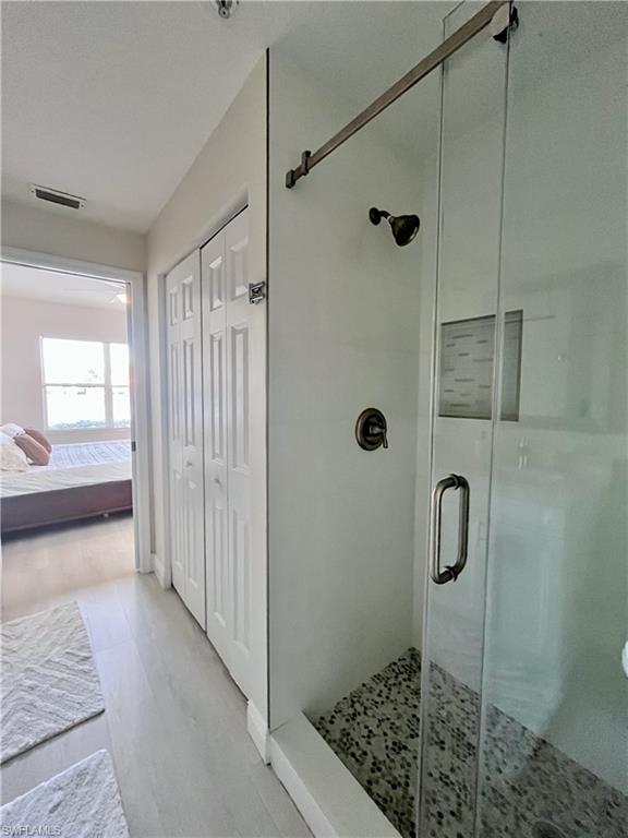 Ensuite bathroom with a closet, a shower stall, and light wood-style flooring
