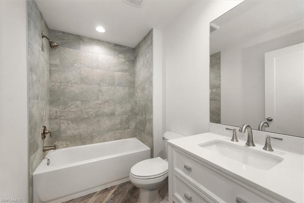 Guest bathroom with 12 x 24 plank porcelain tile to the ceiling. Bathroom vanity has quartz countertops with soft close drawers.