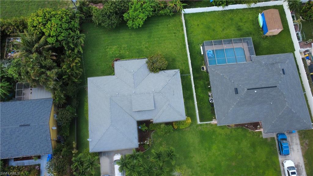 Expansive green lawn surrounds the main residence, featuring a gray shingle roof
