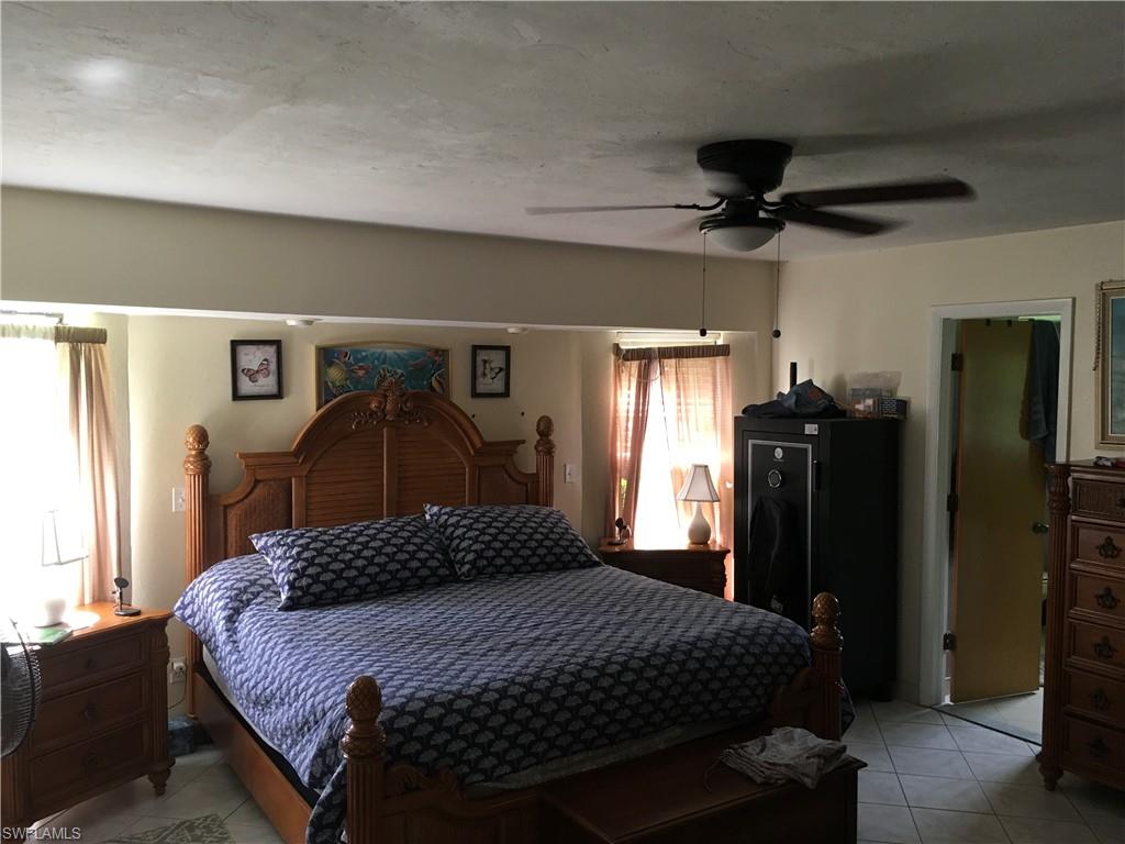Spacious bedroom featuring neutral wall tones, tile flooring, and a ceiling fan with integrated lighting