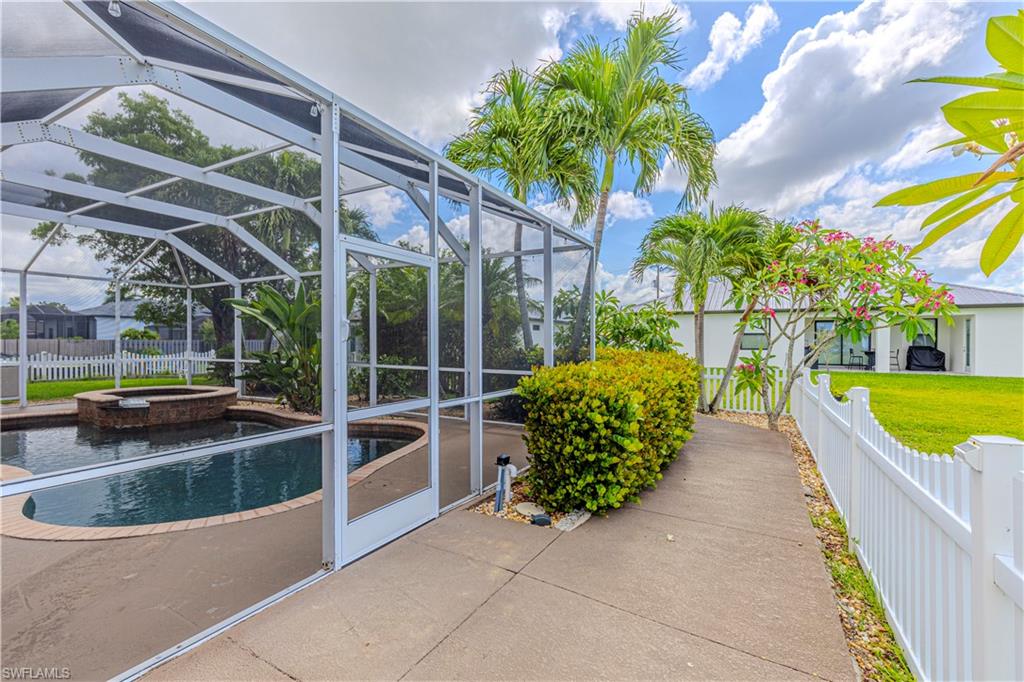Screened pool enclosure featuring a dark-bottom pool with an integrated spa, surrounded by concrete decking