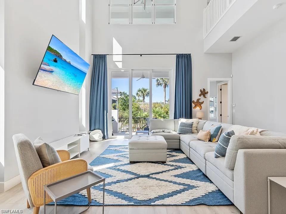 Two-story living area with high ceilings, light wood-finish flooring, and a second-story interior balcony