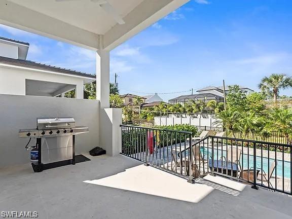 Covered outdoor living area featuring a built-in grill station, concrete flooring, and solid privacy wall