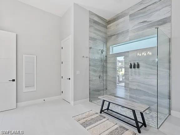 Walk-in shower featuring glass enclosure, full-height tile surround with horizontal veining, a built-in transom window, and a rain showerhead
