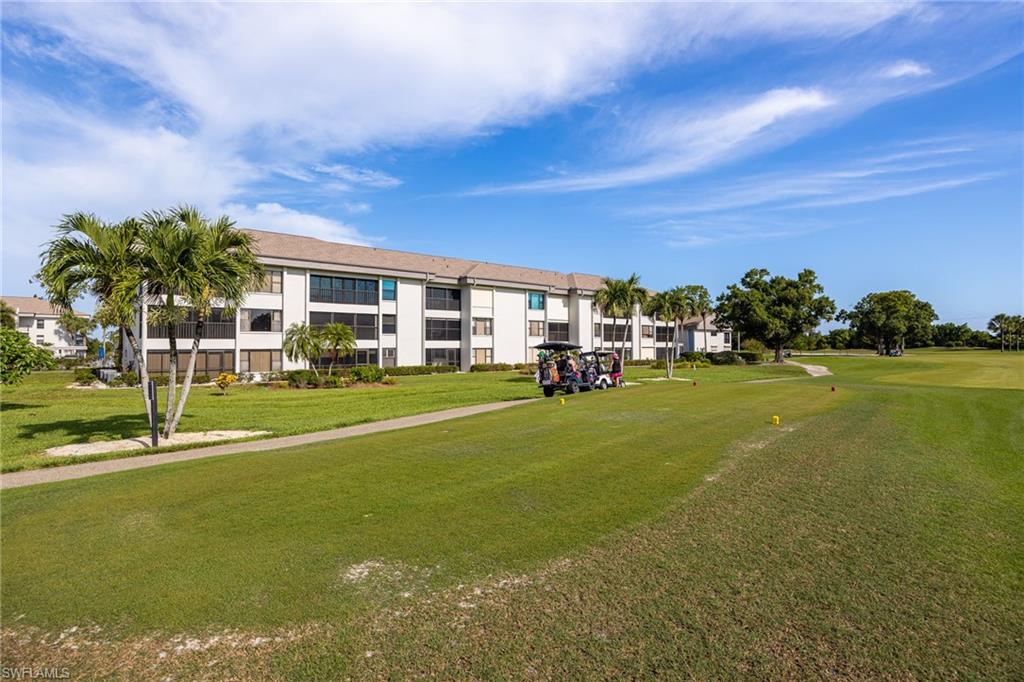 Multi-story residential building with white siding, dark-framed windows, and screened-in balconies
