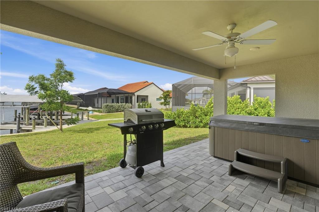 Covered outdoor living space featuring paver flooring, an overhead ceiling fan, and a built-in spa