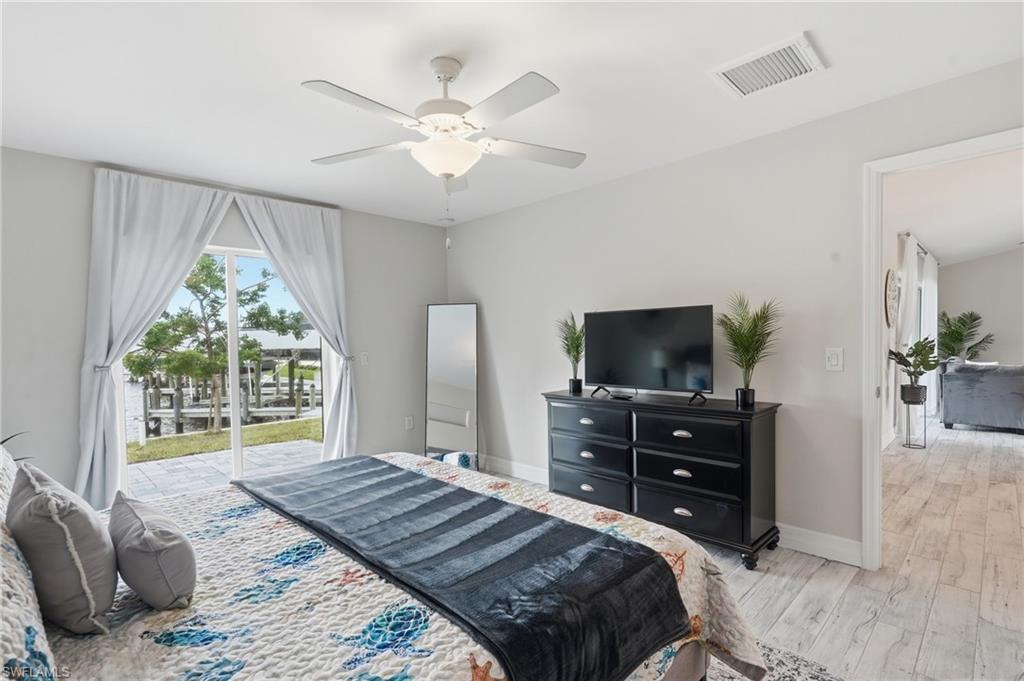 Bedroom featuring glass sliding doors to the exterior, a ceiling fan with integrated lighting, and light wood-finish flooring
