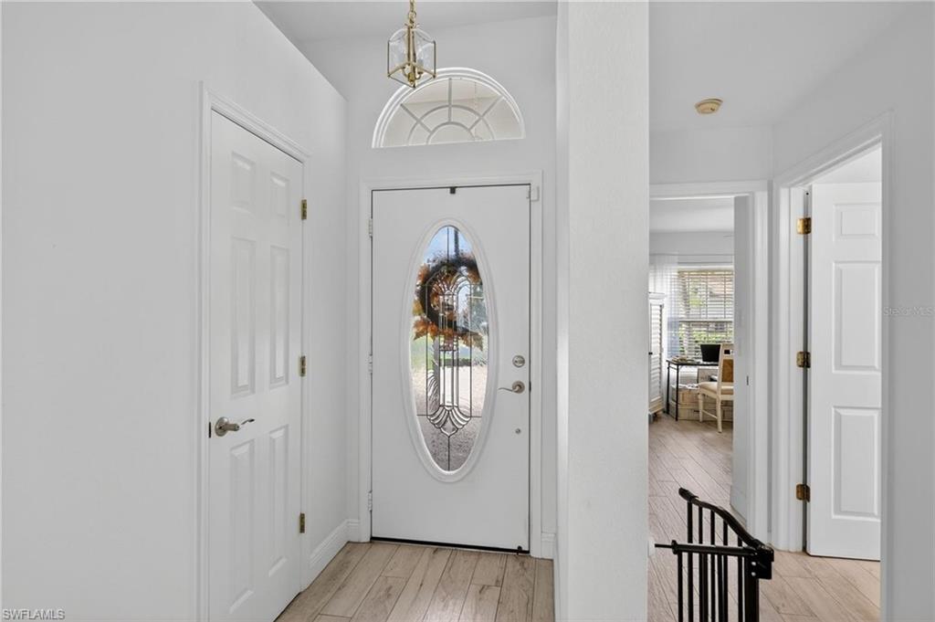 Entryway featuring a decorative glass oval-insert door, an arched transom window, and wood-finish flooring