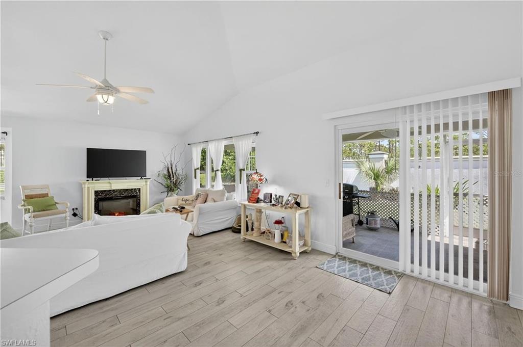Spacious living area featuring light wood-finish flooring and a vaulted ceiling with a ceiling fan