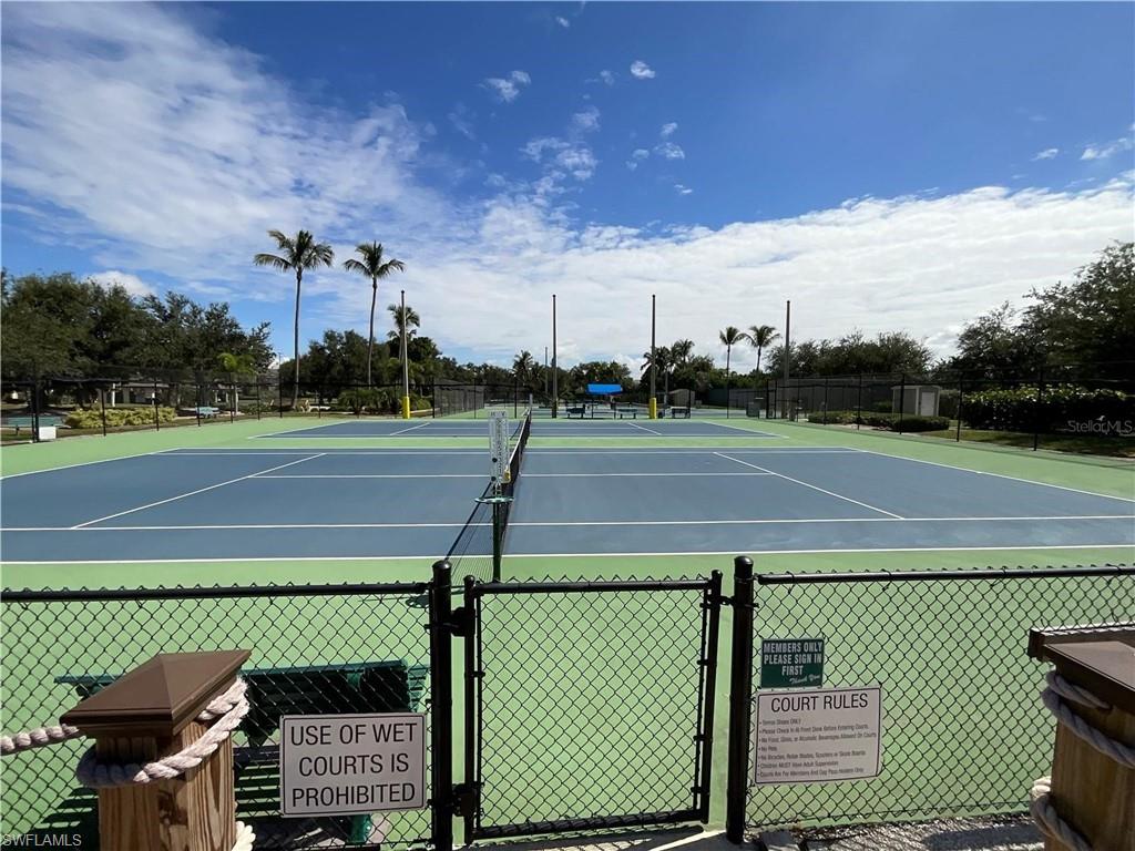 Multiple hard tennis courts with blue playing surfaces and green out-of-bounds areas