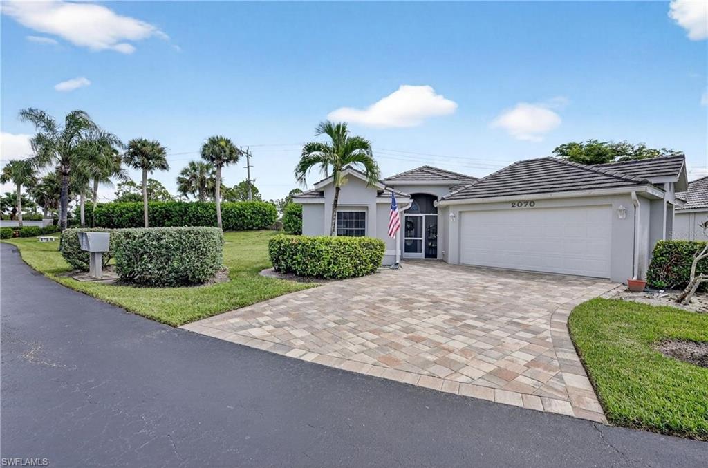 Exterior featuring a paver driveway, an attached garage, a tiled roof, and a screened entry