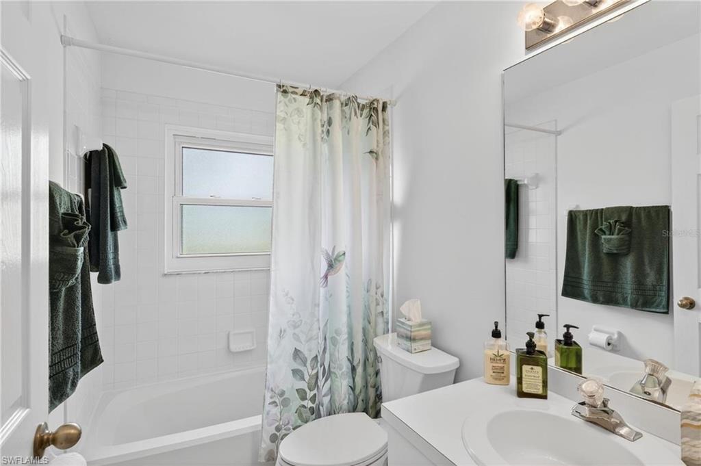 Full bathroom featuring a white tub, white tiled surround, and a vanity with an integrated sink