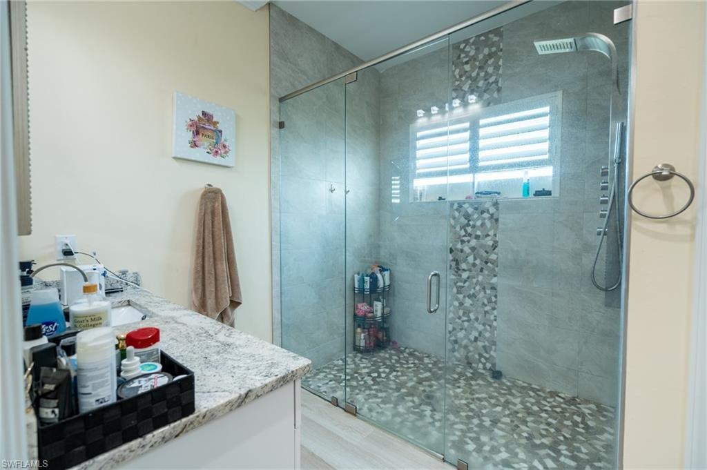 Walk-in shower with full glass enclosure, rainfall showerhead, and mosaic tile accents