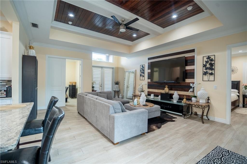 Living area featuring a tiered tray ceiling with recessed lighting and a wood-panel accent