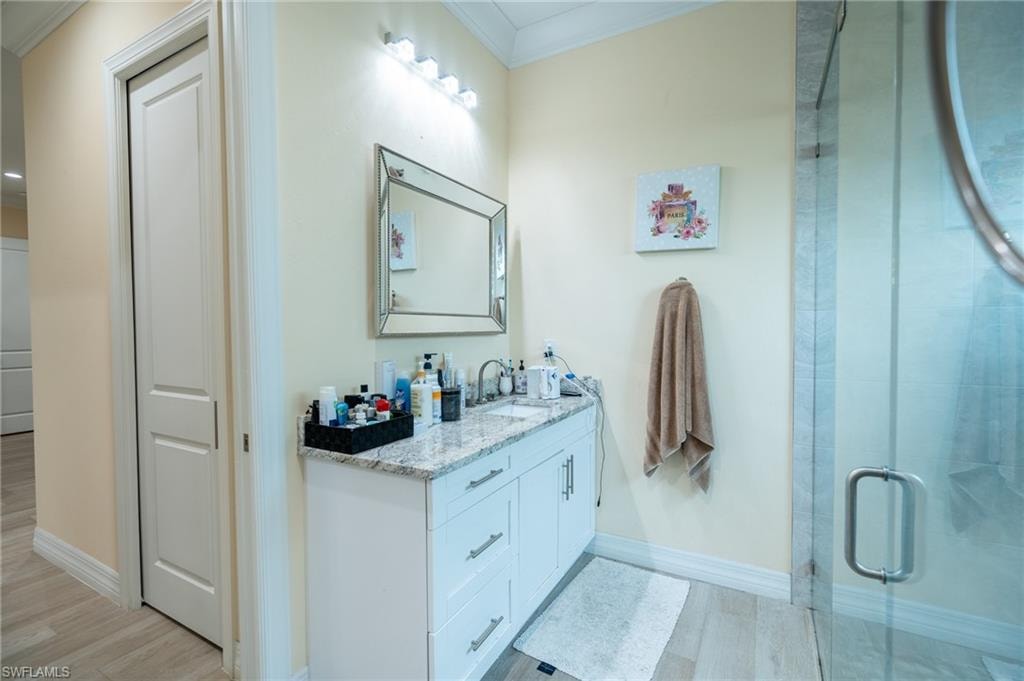 Vanity with dual sinks, granite countertop, and white cabinetry