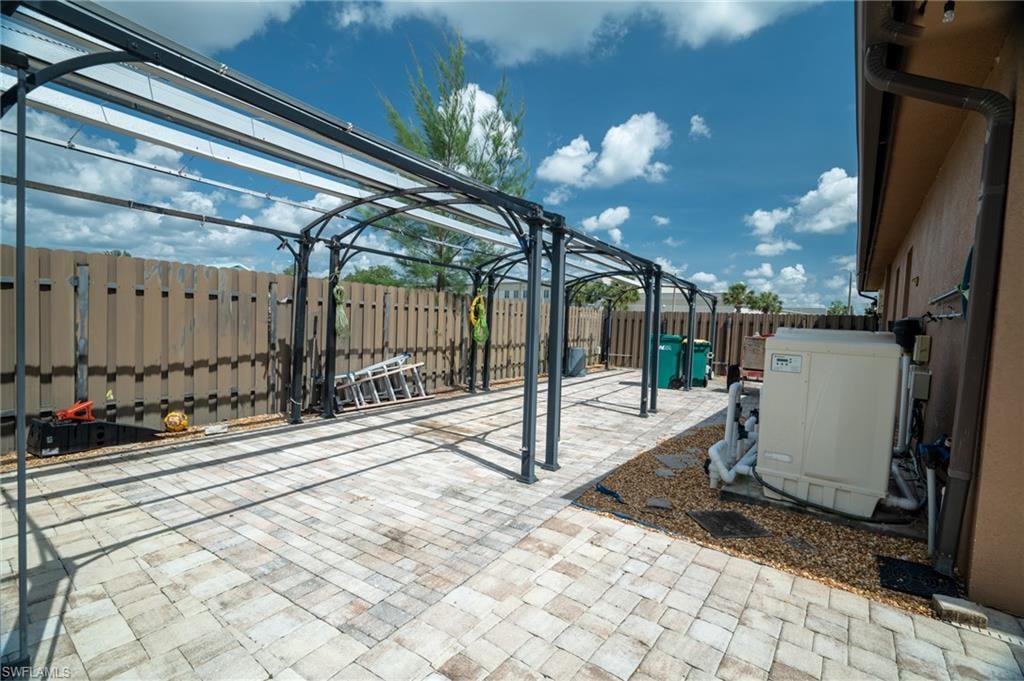 Expansive paved patio featuring a pergola structure with a translucent roof